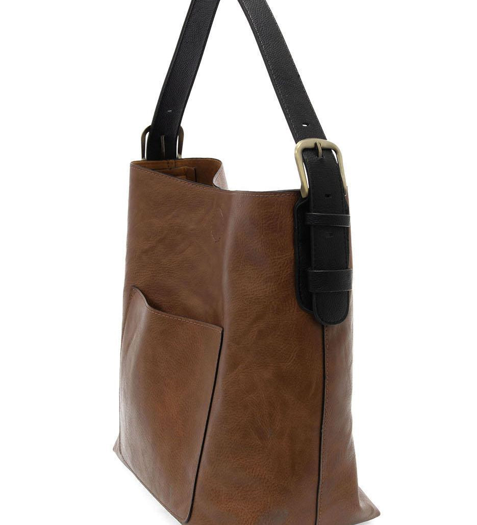 Brown leather tote bag with black handle on a white background. Available at Be Charmed