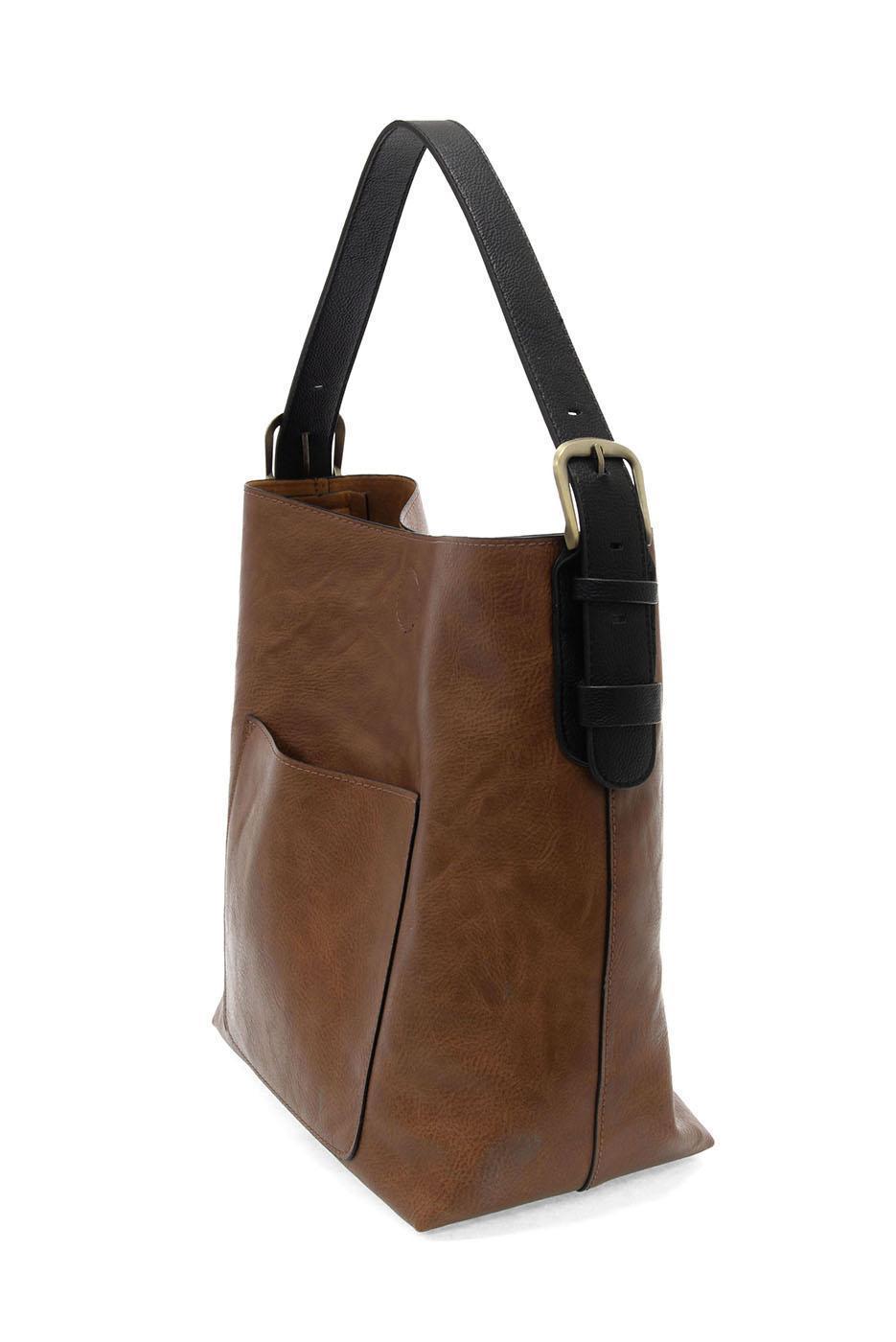 Brown leather tote bag with black handle on a white background. Available at Be Charmed