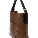 Brown leather tote bag with black handle on a white background. Available at Be Charmed