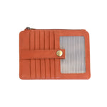 An Joy Susan bonfire orange card holder wallet with multiple card slots, a horizontal strap with a gold snap button, and a clear window showing striped cards inside, set against a plain white background. Available at Be Charmed