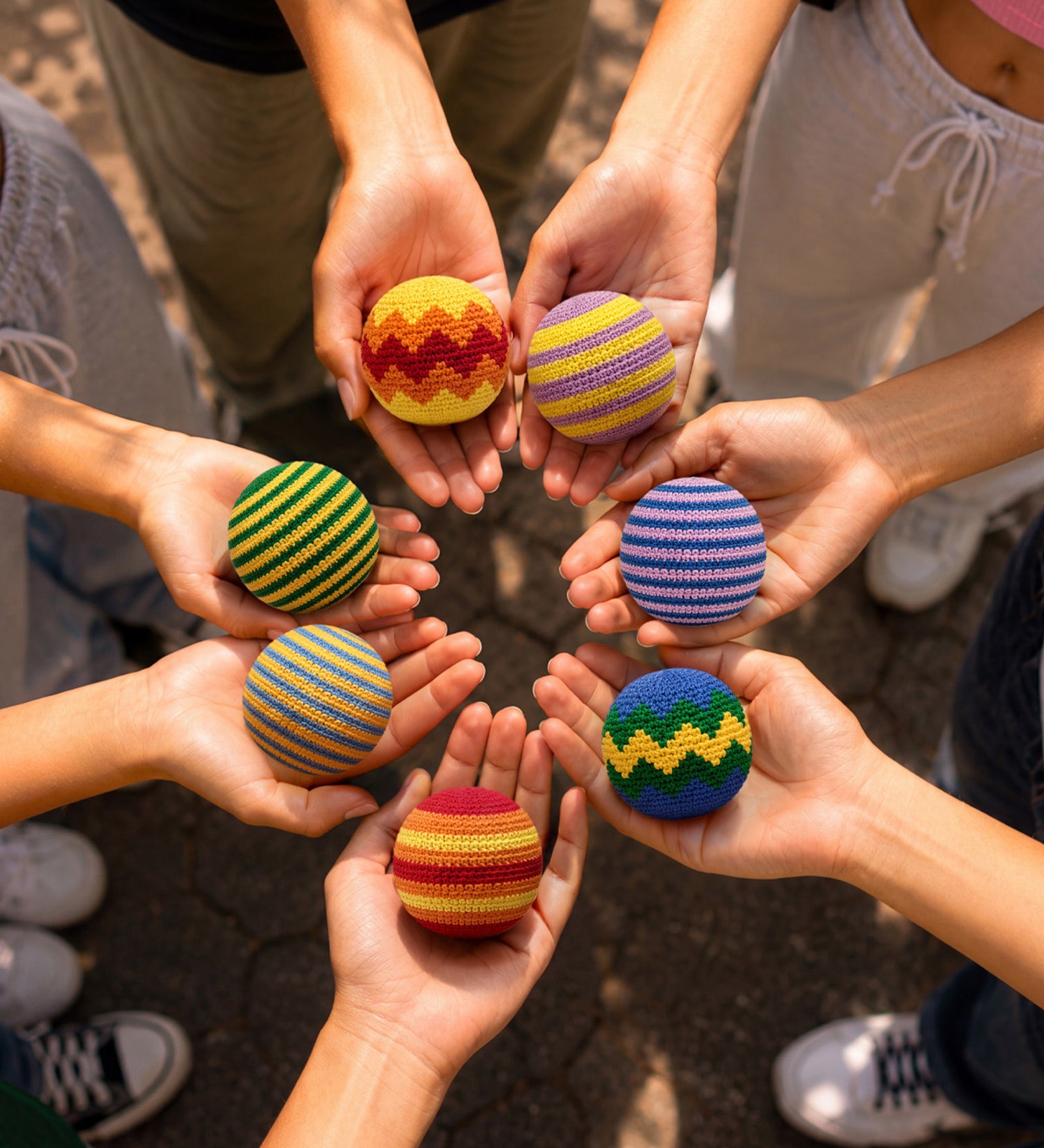 Hands holding colorful striped balls in a circle. Available at Be Charmed