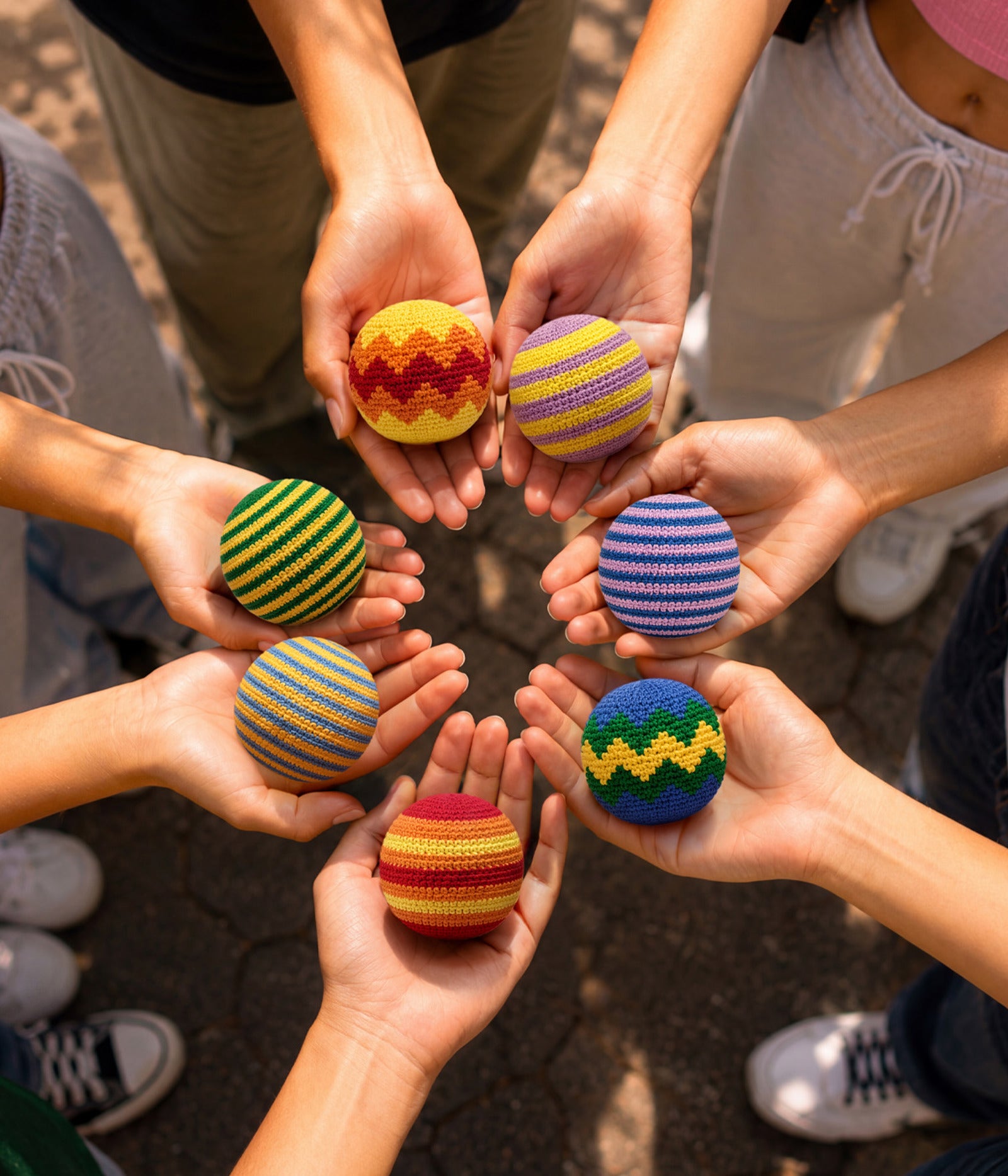 Hands holding colorful striped balls in a circle. Available at Be Charmed