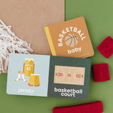 Basketball-themed baby items including a book, cards, and headbands on a green background. Availabe at Be Charmed