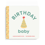 A baby picture book titled 'BIRTHDAY baby' by Danielle Wilson, featuring a cream-colored cover with a yellow party hat illustration and a yellow spine decorated with multicolored sprinkles. Available at Be Charmed
