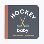 Book titled 'Hockey Baby' with hockey sticks on a dark blue background. Available at Be Charmed