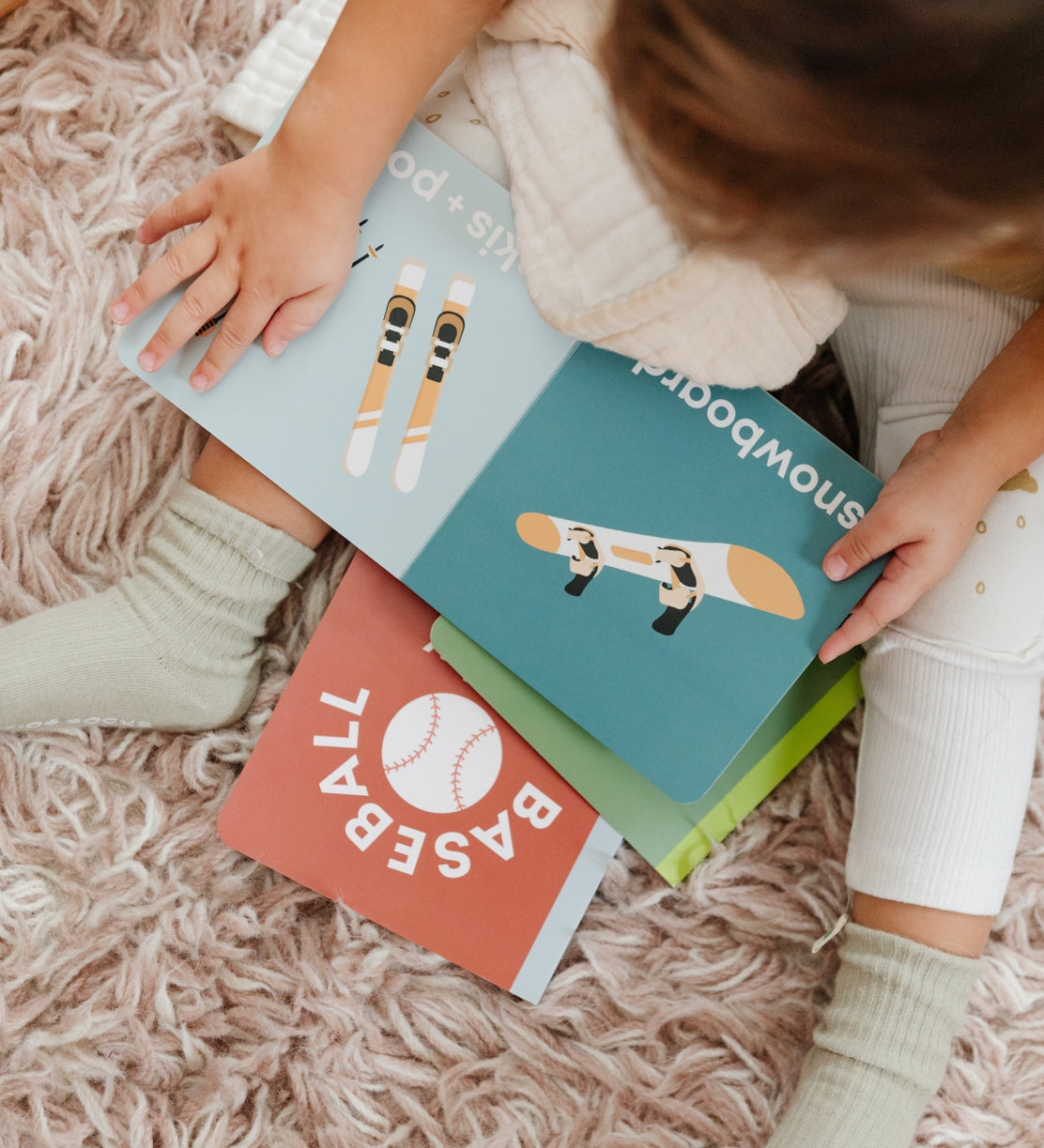 Child holding Left Hand Book House Snow Baby Board Book available at Be Charmed