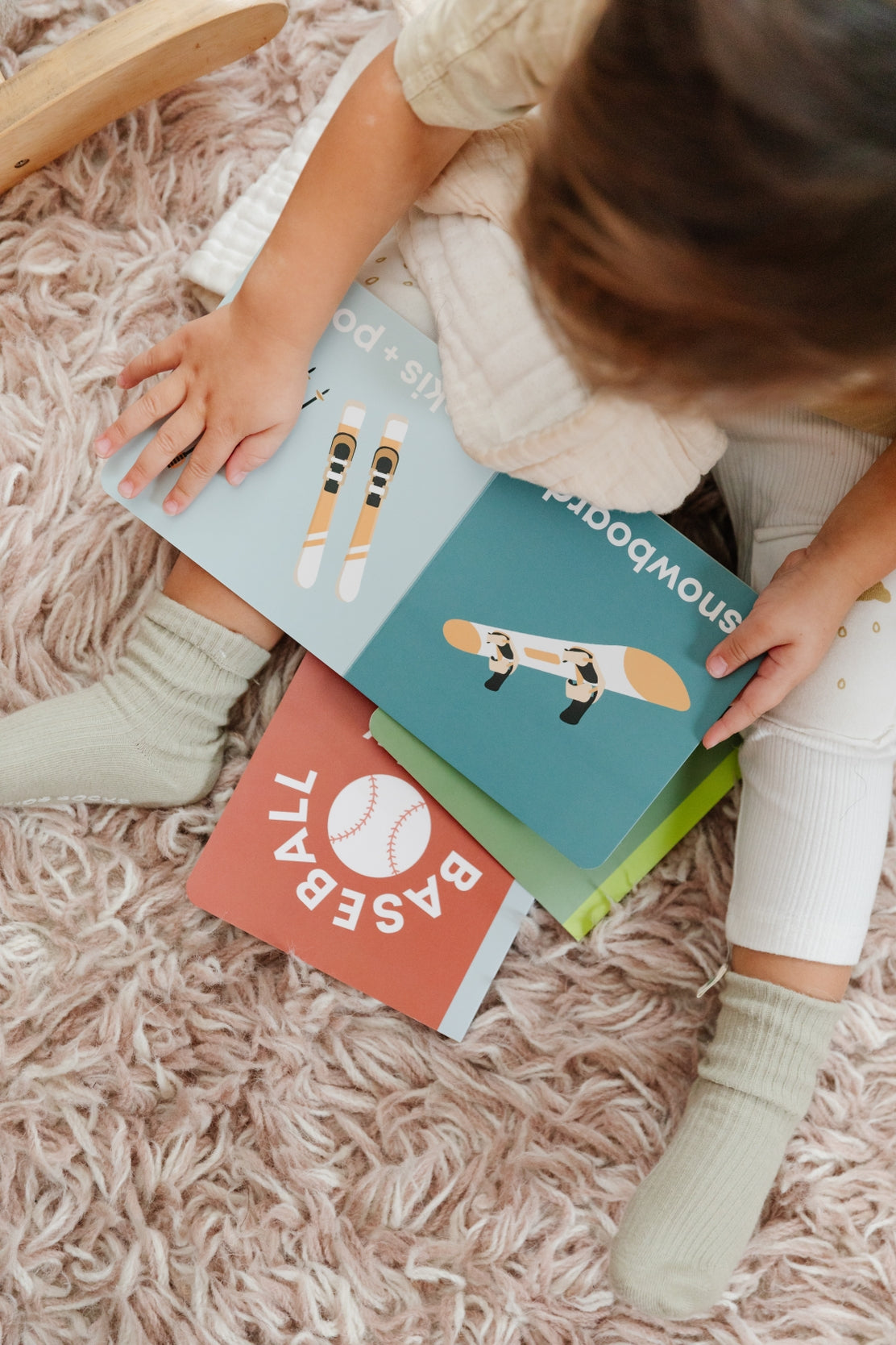 Child holding Left Hand Book House Snow Baby Board Book available at Be Charmed
