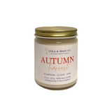 A 7.5 oz soy candle in a clear glass jar with a gold metal lid and a cream-colored label. Available at Be Charmed