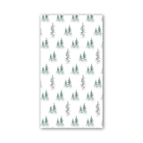 A rectangular napkin featuring a repeating pattern of small evergreen trees in muted green and gray tones, shown against a plain white background. Available at Be Charmed
