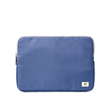 A blue Ori fabric laptop sleeve with a small white brand tag on the bottom right corner, shown against a plain white background. Available at Be Charmed