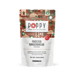 A stand-up pouch of Poppy Hand-Crafted Popcorn in the Frosted Gingerbread flavor, featuring a festive gingerbread-themed pattern on the upper half and white lower half with black text. Available at Be Charmed