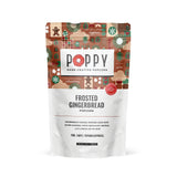 A stand-up pouch of Poppy Hand-Crafted Popcorn in the Frosted Gingerbread flavor, featuring a festive gingerbread-themed pattern on the upper half and white lower half with black text. Available at Be Charmed
