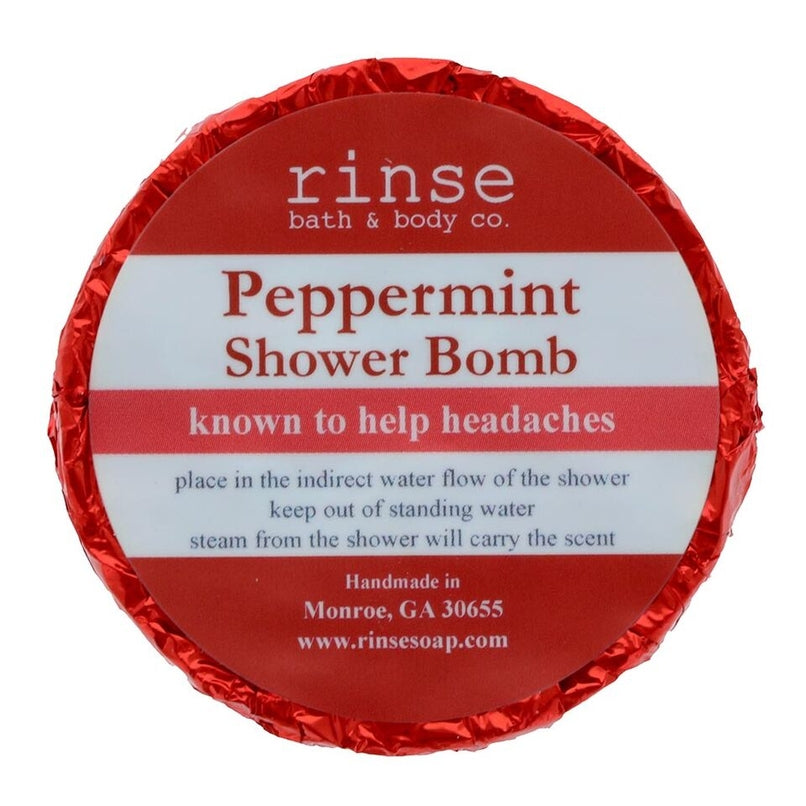 A circular blue shower bomb packaging with a label that reads 'Peppermint Shower Bomb' from Rinse Bath & Body Co. Available at Be Charmed