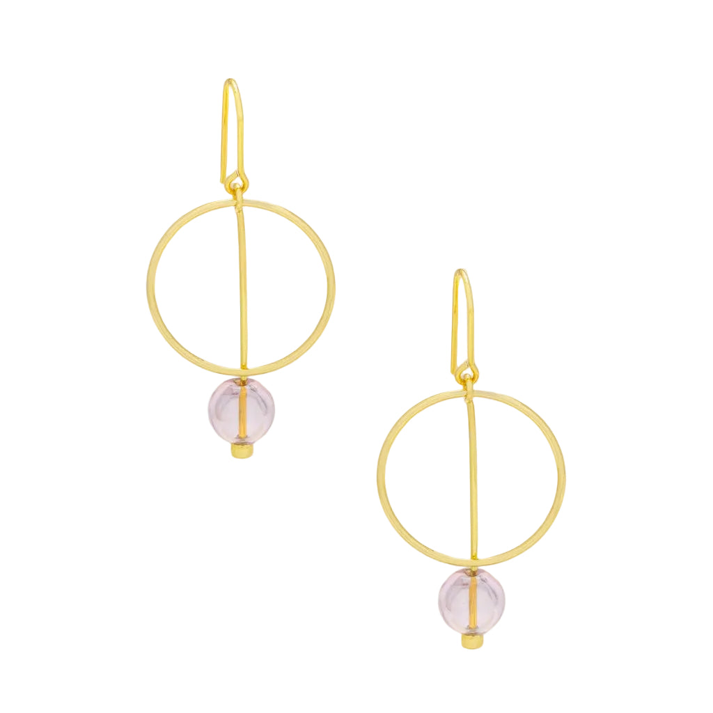 A pair of gold drop earrings with a minimalist circular design and a small light pink bead dangle. Available at Be Charmed
