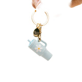 A aqua colored tumbler keychain with a flower detail on a white background, attached to a keyring. Available at Be Charmed