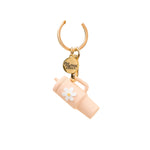 A blush colored tumbler keychain with a flower detail on a white background, attached to a keyring. Available at Be Charmed