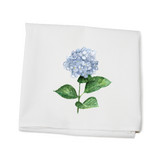 A white kitchen towel with a printed hydrangea flower design and green leaves on it, made of cotton. Available at Be Charmed