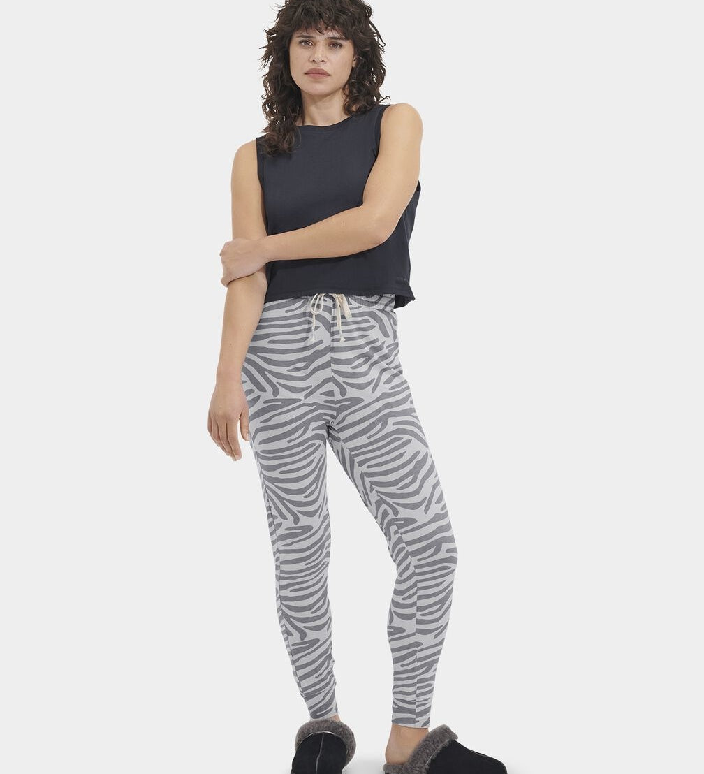 A woman standing, wearing high-waisted drawstring pants with a cloudy grey and white stripe pattern, paired with a black top and black footwear. Available at Be Charmed