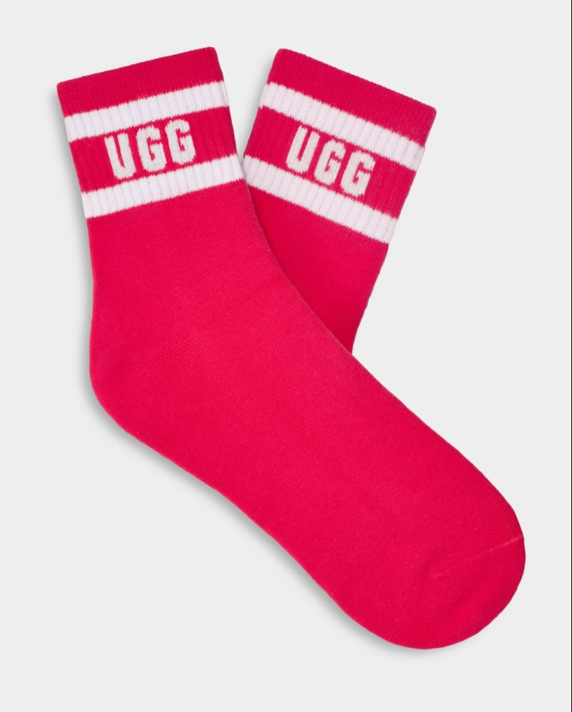 A pair of pink UGG women's socks with white stripes and the UGG logo on the ankle area. Available at Be Charmed