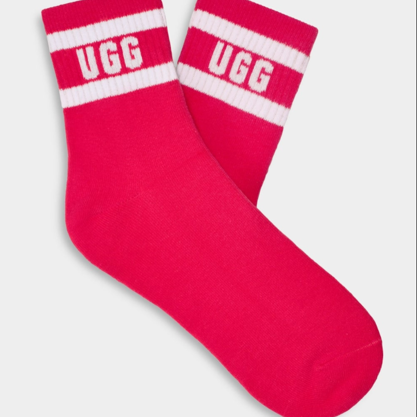 A pair of pink UGG women's socks with white stripes and the UGG logo on the ankle area. Available at Be Charmed
