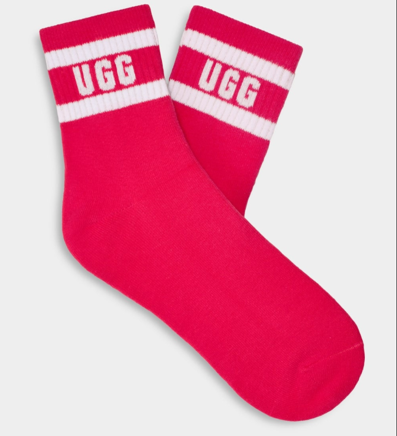 A pair of pink UGG women's socks with white stripes and the UGG logo on the ankle area. Available at Be Charmed