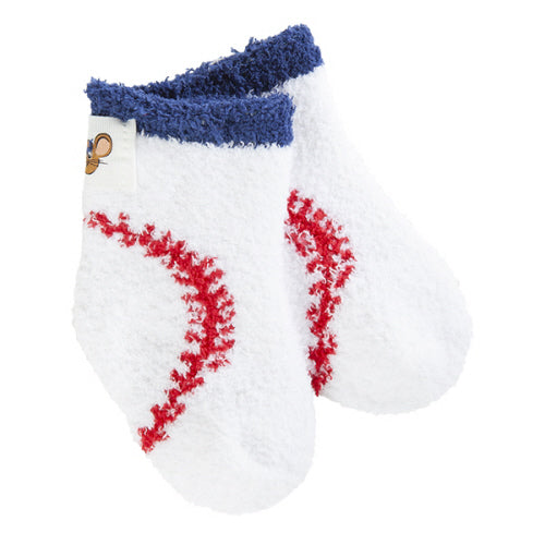 A pair of white plush World's Softest baby socks designed to look like baseballs, featuring red stitched details and a navy blue fuzzy cuff, shown on a plain white background. Available at Be Charmed