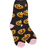 A pair of black fuzzy socks with an all-over orange jack-o'-lantern pattern, featuring pink heels and toes, shown on a plain white background. Available at Be Charmed