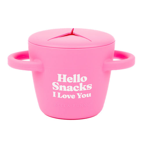 A bright pink siliconeBella Tunno  snack cup with a lid and side handles, featuring the white text 'Hello Snacks I Love You' and 'BELLA TUNNO' on the front, set against a plain white background. Available at Be Charmed