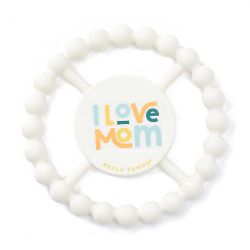 A white silicone baby teether with a circular beaded ring and a central round insert that reads 'I Love Mom' in colorful lettering, with 'BELLA TUNNOP' printed below. Available at Be Charmed