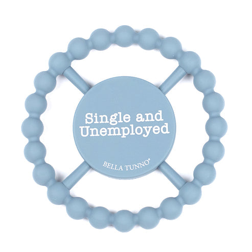 A light blue silicone Bella Tunno baby teether with a circular bead ring and a central wooden spinner disc that reads 'Single and Unemployed' with 'BELLA TUNNO' below it, on a white background. Available at Be Charmed
