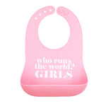 A light pink Bella Tunno silicone baby bib with a darker pink bottom pocket, featuring the white printed text 'who runs the world? GIRLS'. Available at Be Charmed