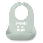A light sage green Bella Tunno silicone baby bib with white text reading 'EMPLOYEE OF THE MONTH' and a small 'BRICK BRICK COMPANY' logo below, shown on a plain white background. Available at Be Charmed