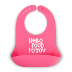 A bright pink Bella Tunno silicone baby bib with a white printed text design that reads 'Hello food I <heart> you' on a clean white background. Available at Be Charmed