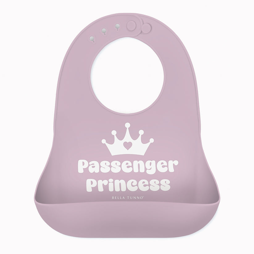 A light purple Bella Tunno silicone baby bib with a white crown graphic and the words 'Passenger Princess' printed on the front, set against a plain white background. Available at Be Charmed