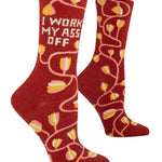 Red socks with yellow tulip pattern and text 'I WORK MY ASS OFF' on a white background. Available at Be Charmed