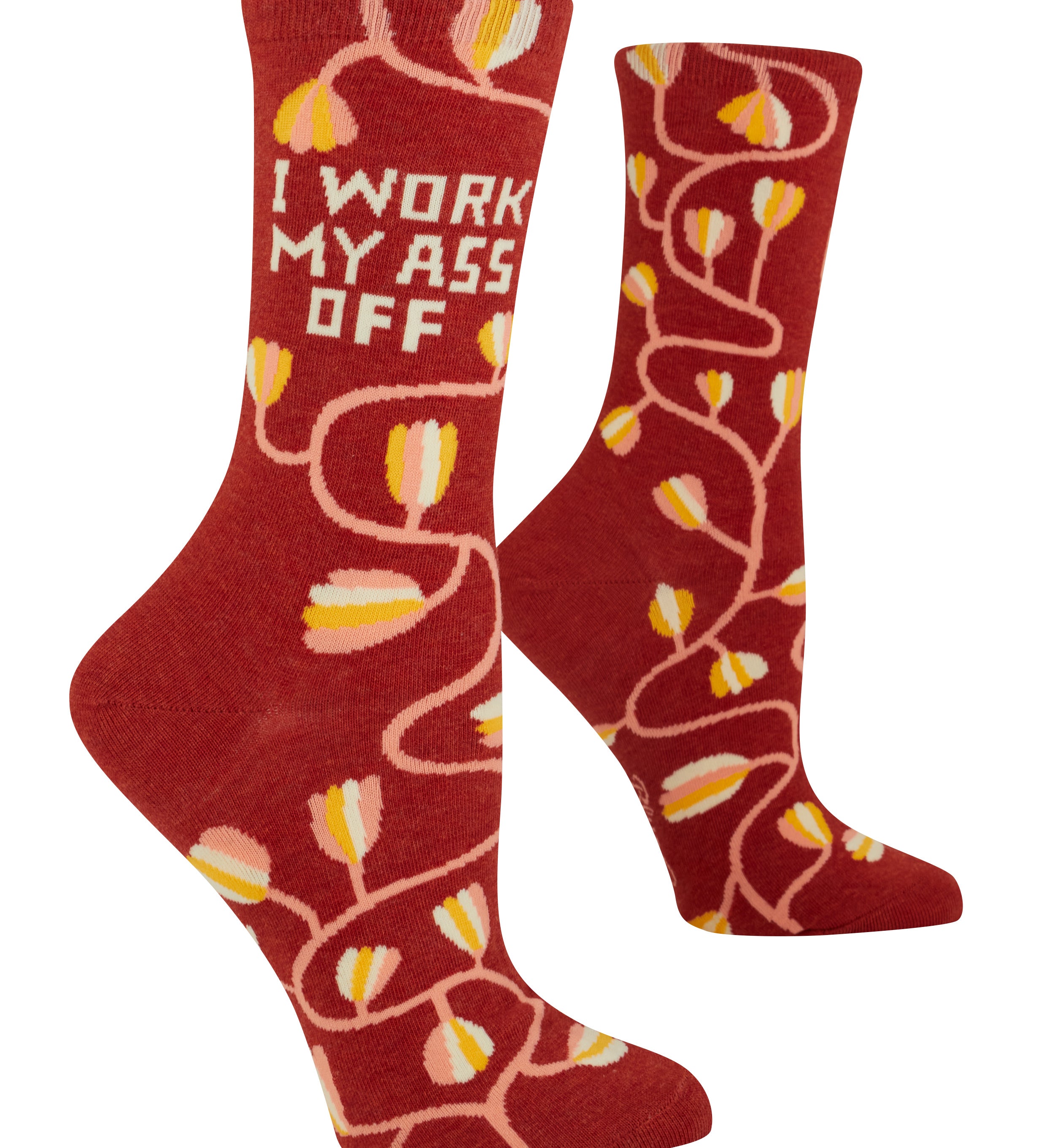Red socks with yellow tulip pattern and text 'I WORK MY ASS OFF' on a white background. Available at Be Charmed