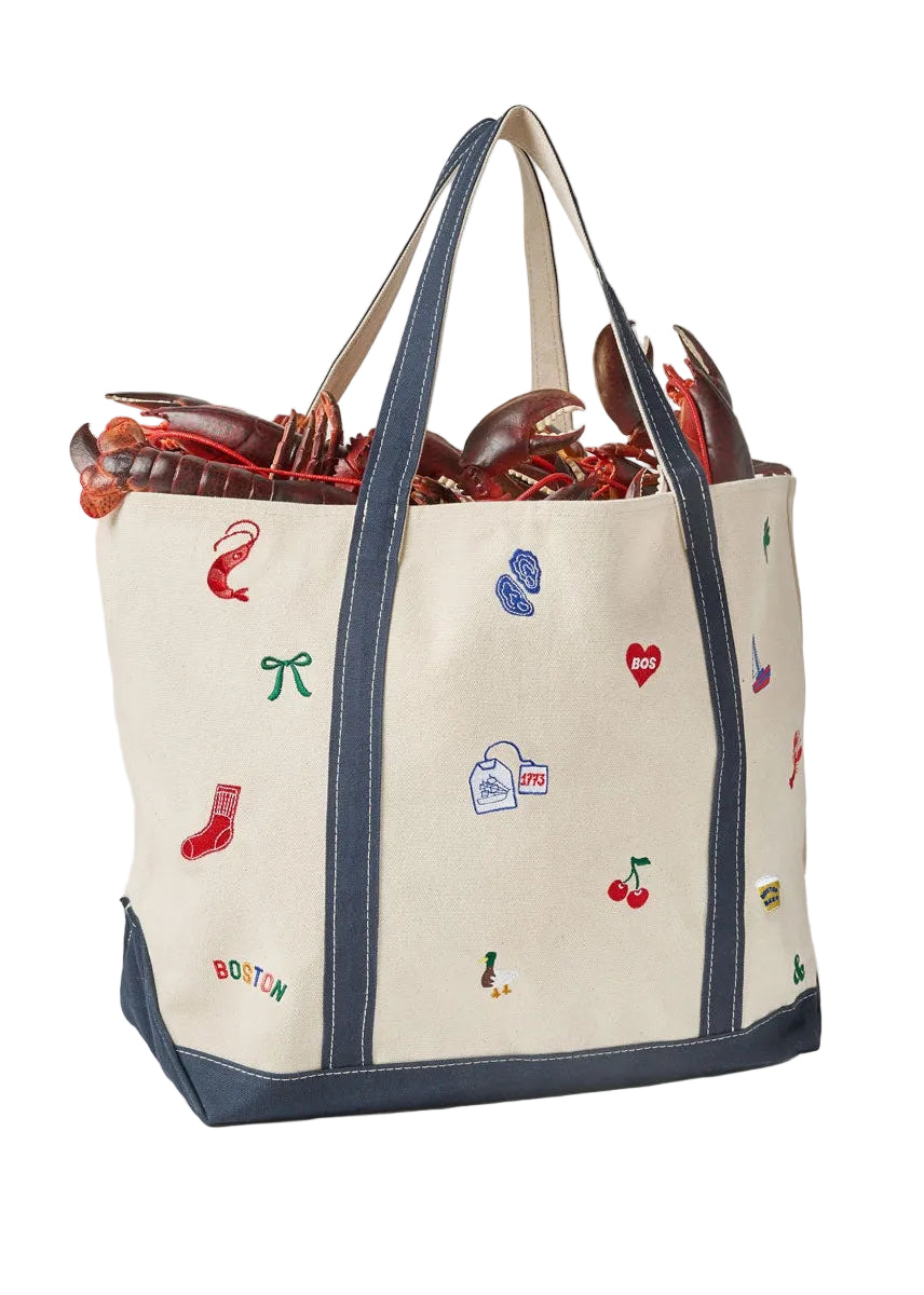 Back of an Alice & Wonder off-white canvas tote bag with navy blue trim and handles, decorated with colorful embroidered lobster-themed motifs including a lobster, red sock, blue cleats, and cherries. The bag is shown filled with lobsters against a light gray background. Available at Be Charmed