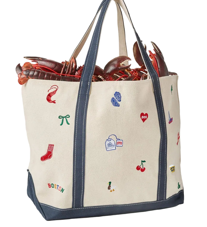 Back of an Alice & Wonder off-white canvas tote bag with navy blue trim and handles, decorated with colorful embroidered lobster-themed motifs including a lobster, red sock, blue cleats, and cherries. The bag is shown filled with lobsters against a light gray background. Available at Be Charmed