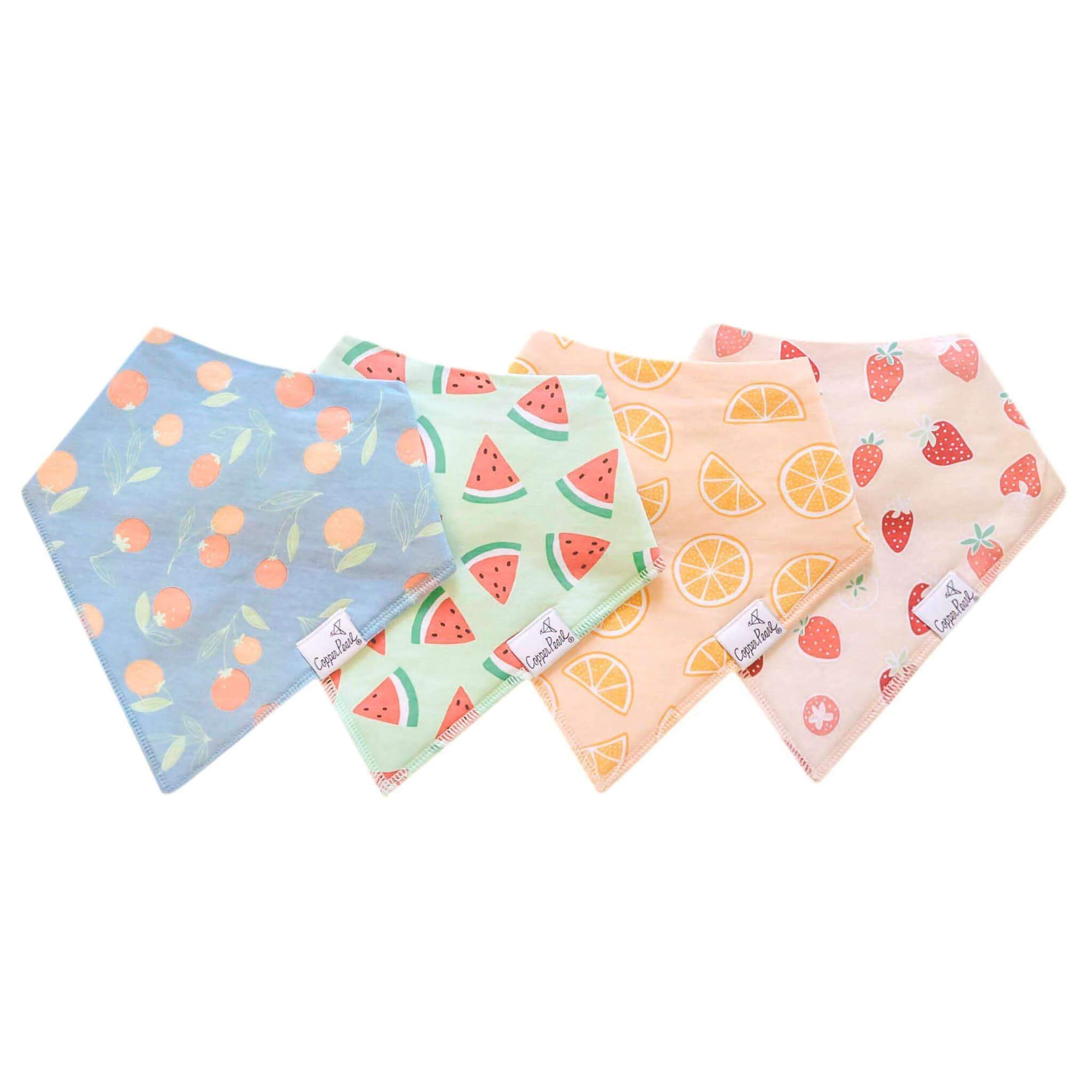 Four colorful bandana bibs with fruit patterns on a white background. Available at Be Charmed
