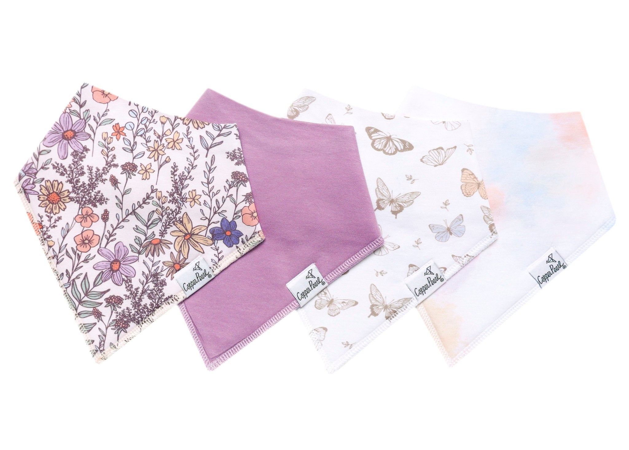 Set of four bibs with floral, purple, and butterfly patterns on a white background. Available at Be Charmed