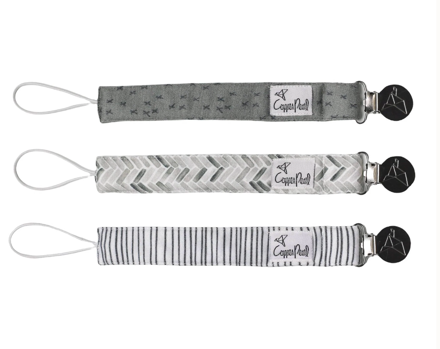 Three patterned pacifier clips on a white background, featuring different designs. Available at Be Charmed