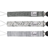 Three patterned pacifier clips on a white background, featuring different designs. Available at Be Charmed