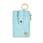 Light blue cardholder with gold accents on a beige background. Available at Be Charmed