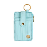Light blue cardholder with gold accents on a beige background. Available at Be Charmed