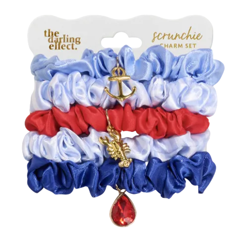 Set of scrunchies with charms on a branded card, featuring blue, red, and white colors. Available at Be Charmed