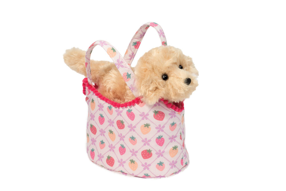 Small plush dog inside a pink bag with strawberry pattern on a white background. Available at Be Charmed