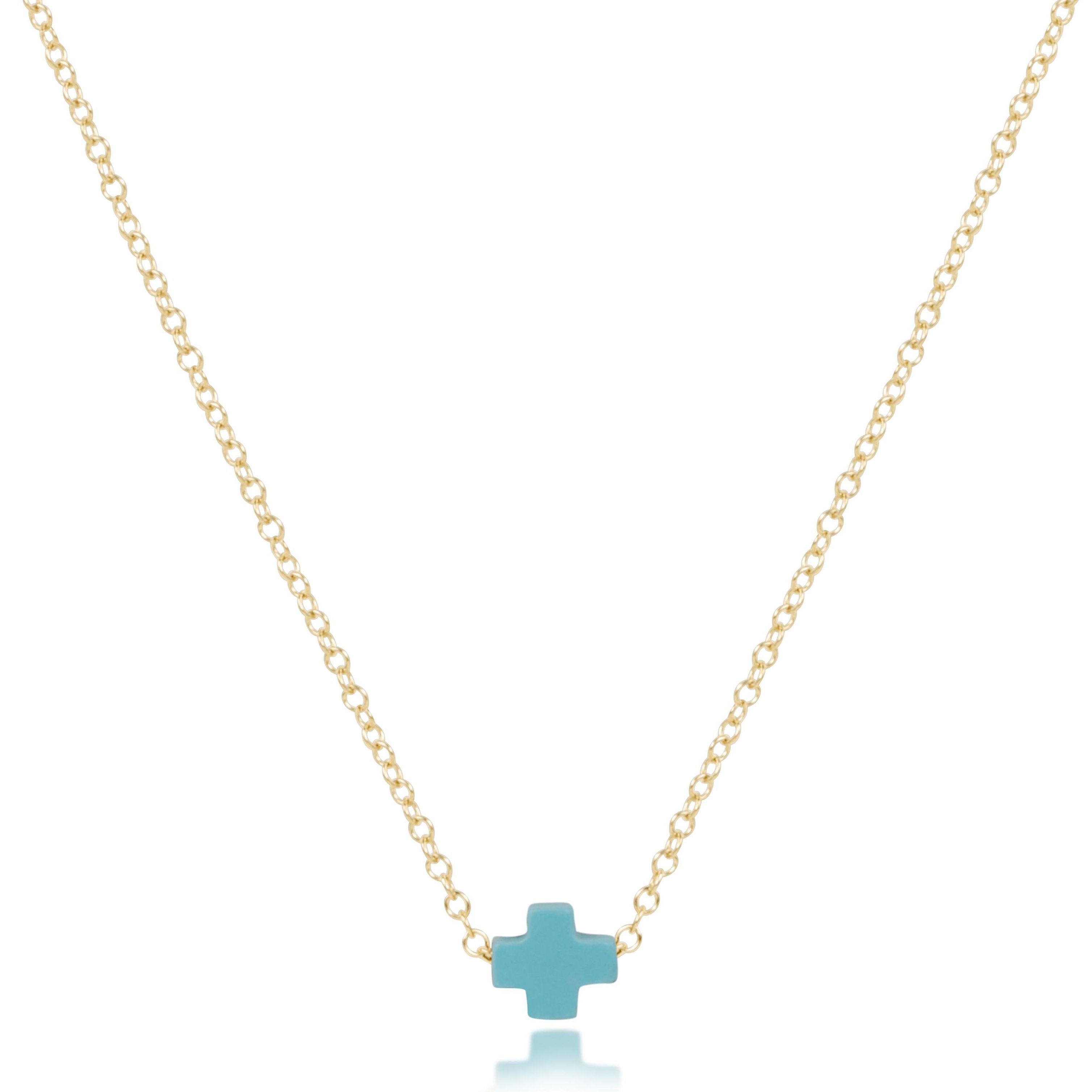enewton Gold necklace with a turquoise cross pendant on a white background. Available at Be Charmed