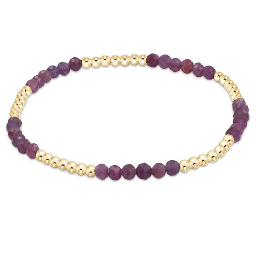 A bracelet with a series of round beads, featuring a deep ruby color with gold-filled bands. Available at Be Charmed
