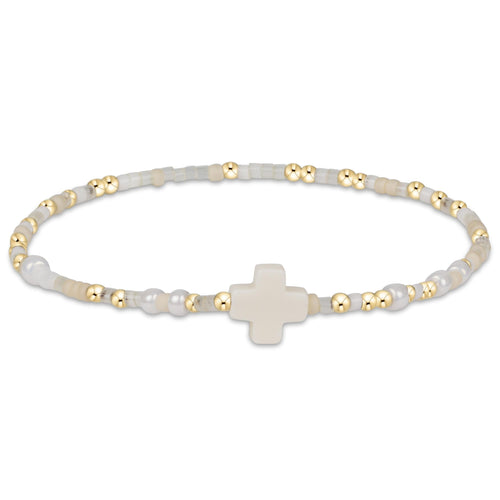 enewton Hope Unwritten Signature Cross Bracelet – Call Me On My Shellphone with cross charm, shellphone bead, and 14k gold-filled beads. Stackable and water-friendly. Available at Be Charmed.