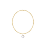 Gold bracelet with a single pearl charm on a white background. Available at Be Charmed